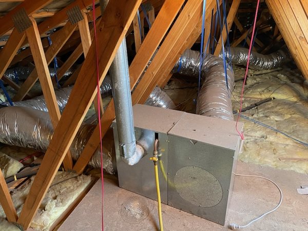 Ducted gas heater unit in a roof space, with silver flexible ducts and a yellow gas line